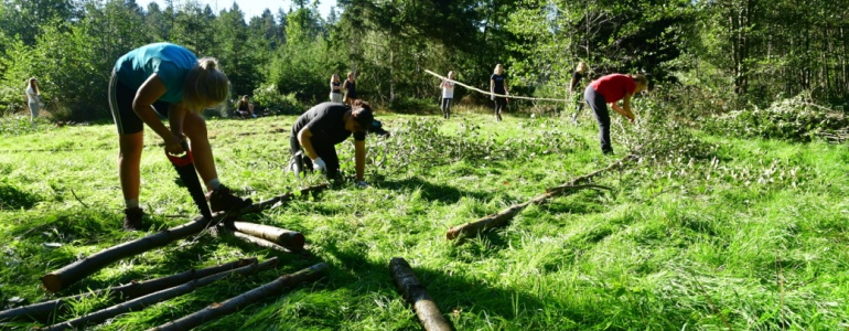 Studenti řežou pilou kmen.